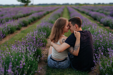 young couple in love man and girl on a walk on the street in nature under the open sky hugging and kissing. Lavender field with purple flowers for a romantic couple of people in love
