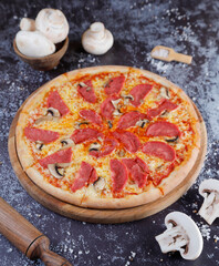 Hot tasty traditional various italian pizzas with salami, meat, cheese, onion, mushroom, tomatoes greens on a dark background