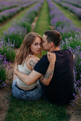 young couple in love man and girl on a walk on the street in nature under the open sky hugging and kissing. Lavender field with purple flowers for a romantic couple of people in love