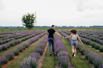 young couple in love man and girl on a walk on the street in nature under the open sky hugging and kissing. Lavender field with purple flowers for a romantic couple of people in love