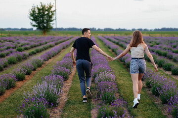 young couple in love man and girl on a walk on the street in nature under the open sky hugging and kissing. Lavender field with purple flowers for a romantic couple of people in love