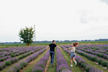 young couple in love man and girl on a walk on the street in nature under the open sky hugging and kissing. Lavender field with purple flowers for a romantic couple of people in love