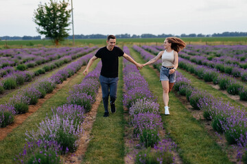 young couple in love man and girl on a walk on the street in nature under the open sky hugging and kissing. Lavender field with purple flowers for a romantic couple of people in love
