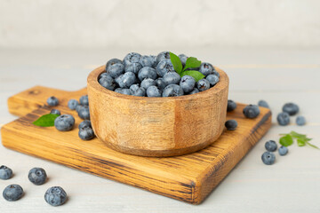 Bowl with fresh bright blueberries on wooden table
