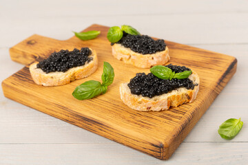 Bread slice with black caviar served on on wooden table
