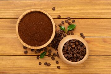 Roasted coffee beans with leaves on wooden background,top view