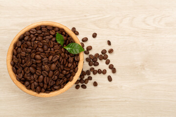 Roasted coffee beans with leaves on wooden background,top view
