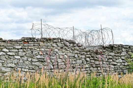 Prison wall with barbed wire, ruins of the abandoned Soviet prison in Rummu, Estonia