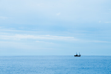 Fototapeta premium fishing boat on calm ocean horizon.
