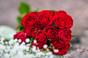 bouquet of vibrant red roses with white flowers.