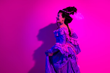 Elegant woman in historic royal dress highlighted by vibrant ultraviolet lighting in a modern artistic interpretation of baroque style