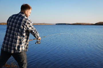 Fisherman with rod fishing at riverside. Recreational activity