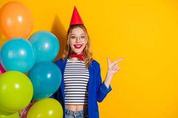 Excited young woman in stylish outfit celebrating with colorful balloons and vibrant yellow...