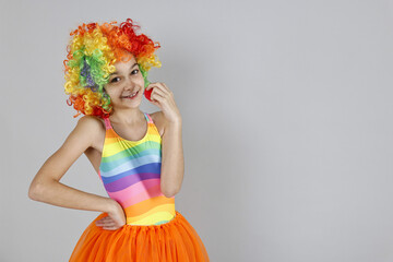 Happy girl dressed like clown on grey background, space for text. Surprise party