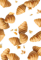 Delicious croissants and crumbs in air on white background. Puff pastry