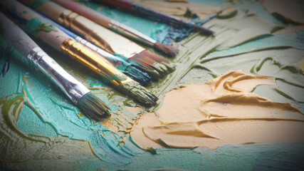 Artist's palette with many brushes and mixed paints, closeup