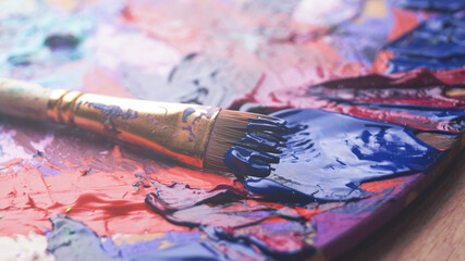 Obraz premium Artist's palette with brush and mixed paints, closeup