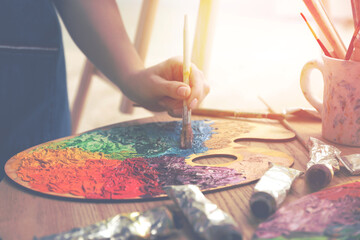 Artist mixing paints with brush on palette, closeup