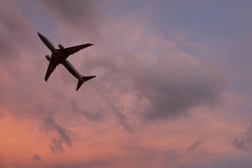 Airplane flying in beautiful sky with clouds at sunset