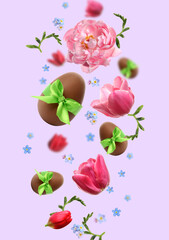 Chocolate eggs and beautiful spring flowers in air on pastel light violet background