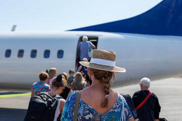 Passengers boarding a small airplane on a sunny day at the airport