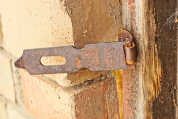 one old rusty brown historical industrial retro iron nailed door security open bracket with hole near brick wall day outside
