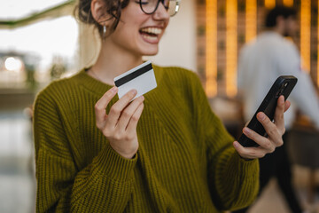 young woman use credit card for online shopping on cellphone at cafe