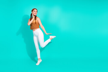 Stylish young woman in trendy summer outfit posing cheerfully against a teal background, radiating happiness and charm