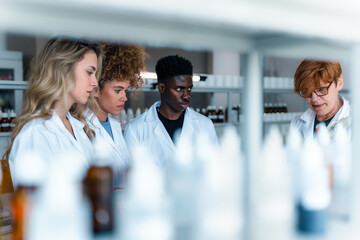 Multi ethnic group of pharmacy students and their professor working together in university...