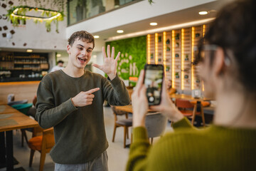 girlfriend use mobile phone to record video of her boyfriend at cafe