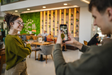 boyfriend use mobile phone to record video of his girlfriend at cafe