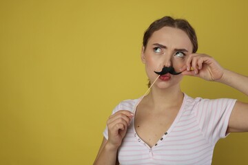 Funny woman with fake paper mustache on light green background. Space for text