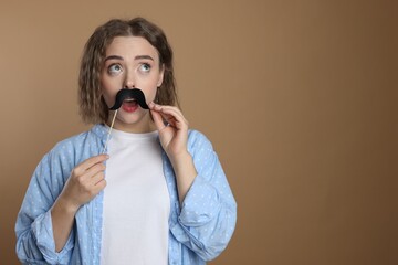 Woman with fake paper mustache on beige background. Space for text