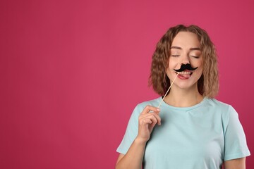 Happy woman with fake paper mustache on pink background. Space for text