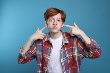 Funny teenage boy with freckles on light blue background