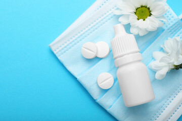 Allergy treatment. Nasal drops, pills, flowers and protective mask on light blue background, flat...