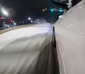 Obraz premium A car is driving down a snowy road at night