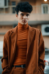 Fototapeta premium Stylish man in brown outfit with a turtleneck and blazer against an urban backdrop