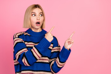 Expressive young woman wearing a striped sweater pointing with her fingers against a pink background