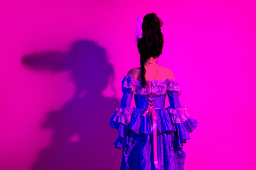 Elegant woman in vintage costume with vibrant neon light creating historical and modern atmosphere