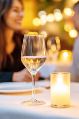 A romantic dinner scene showing two glasses of wine with a candle in the background, creating a cozy and intimate atmosphere for a couple enjoying their time together.