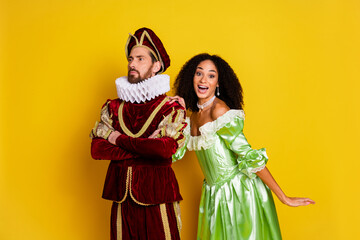 Young couple dressed in vintage costumes with a modern twist pose against a vibrant yellow...