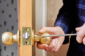 Door installer secures handle and latch to interior door using hand screwdriver.