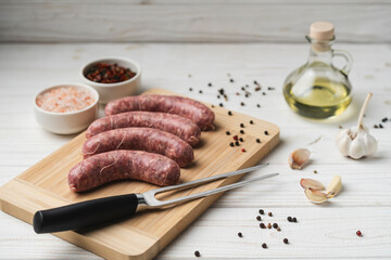 Uncooked grilled sausages on the wooden cutting board