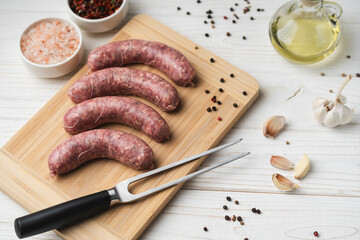 Uncooked grilled sausages on the wooden cutting board