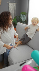 Obraz premium Woman interacting with young boy in modern living room highlights family bond with relaxed atmosphere and natural light surrounding them in a cozy, stylish apartment setting.