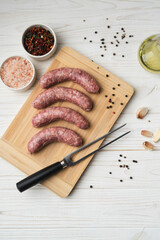Uncooked grilled sausages on the wooden cutting board