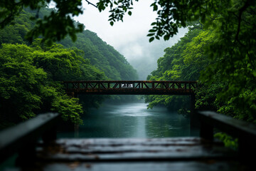 Fototapeta premium A weathered stone bridge arching over a misty river, surrounded by lush green hills, evoking a sense of forgotten history and timeless beauty.