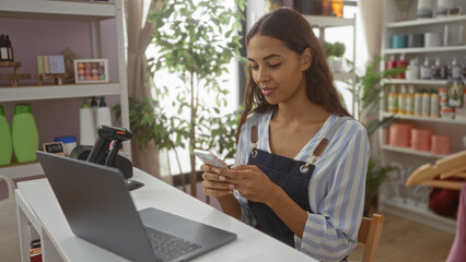 Woman using a smartphone in a home decor store, with various products displayed on shelves in the...
