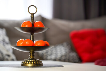 Two-tier fruit stand with fresh tangerines in a cozy interior